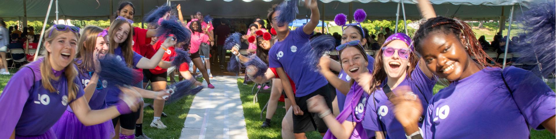 Orientation leaders shake pom poms and noisemakers for new students